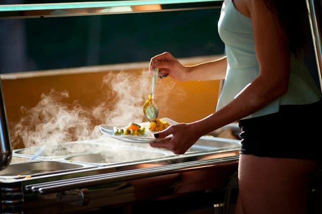 Mujer sirviendose comida en servicio de catering